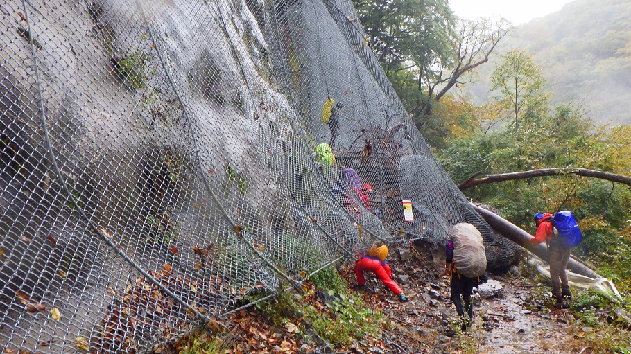 易老渡登山口の手前、落石防止の金網が崩落で林道に大きく張り出している。金網の下をくぐった