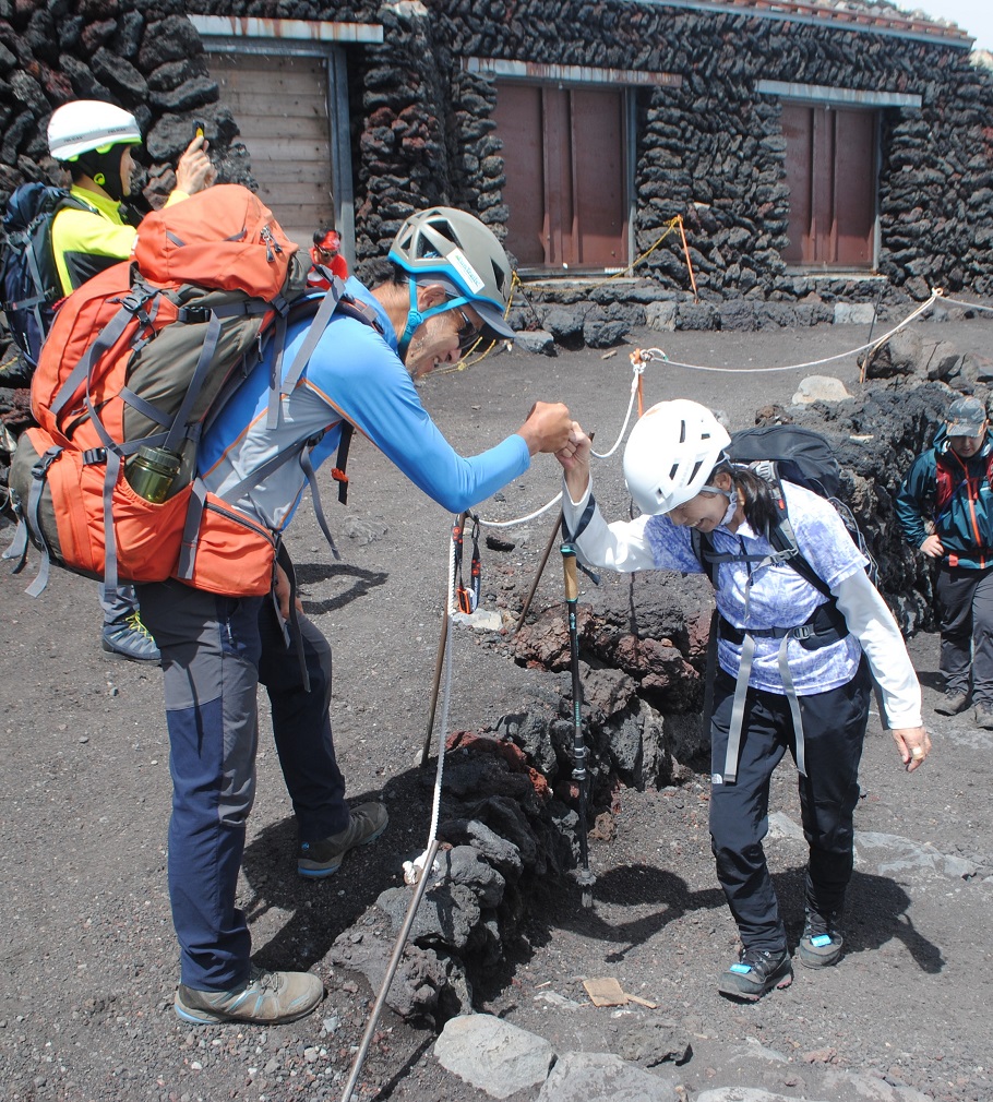 ついに富士山の山頂へ。楠元ガイドとグータッチする参加者