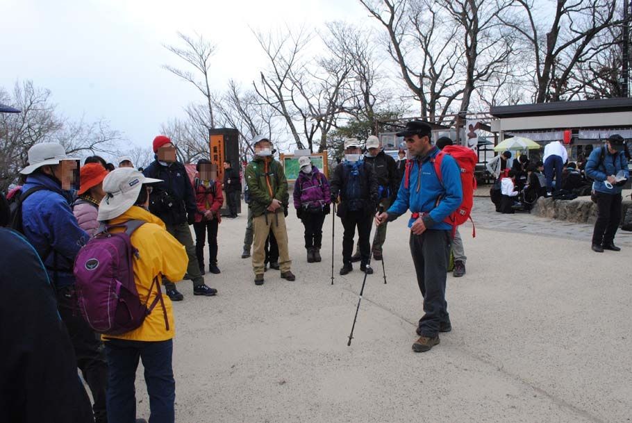 高尾山山頂でストックの使い方について話をする上村博道・登山ガイド