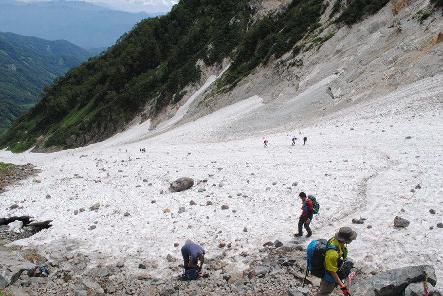 白馬大雪渓の終点。落石が転々と転がっている中を登山者が登って来る